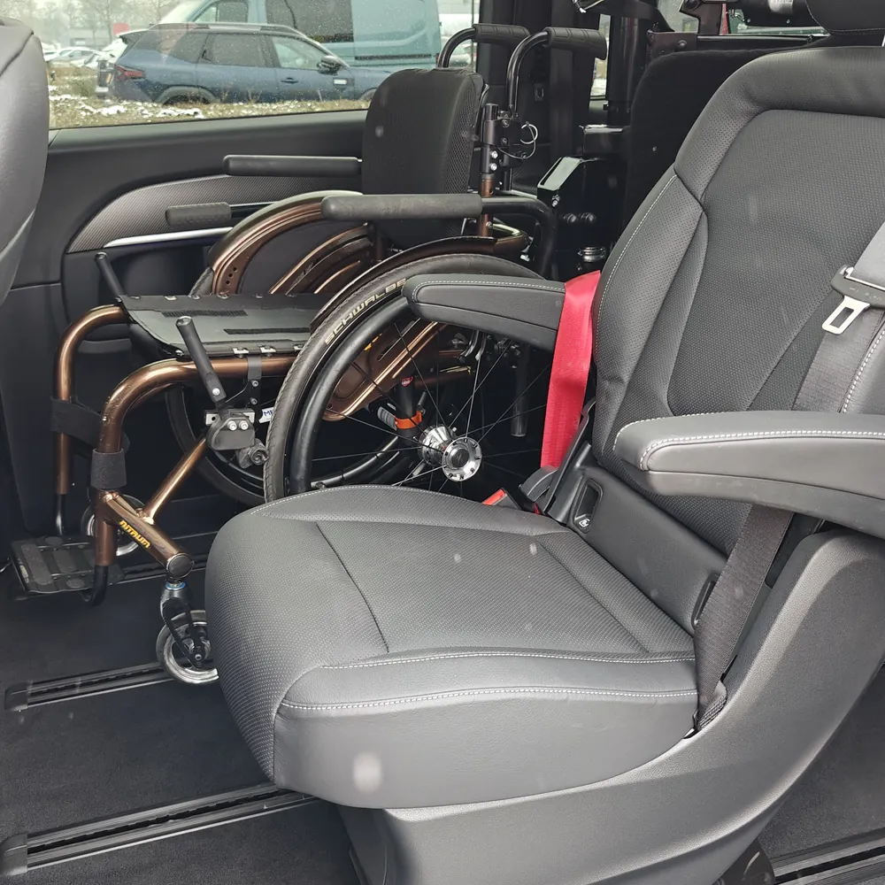 Rollstuhl gesichert in der zweiten Sitzreihe neben einem Originalsitz im Personenbus mit Rolpollo